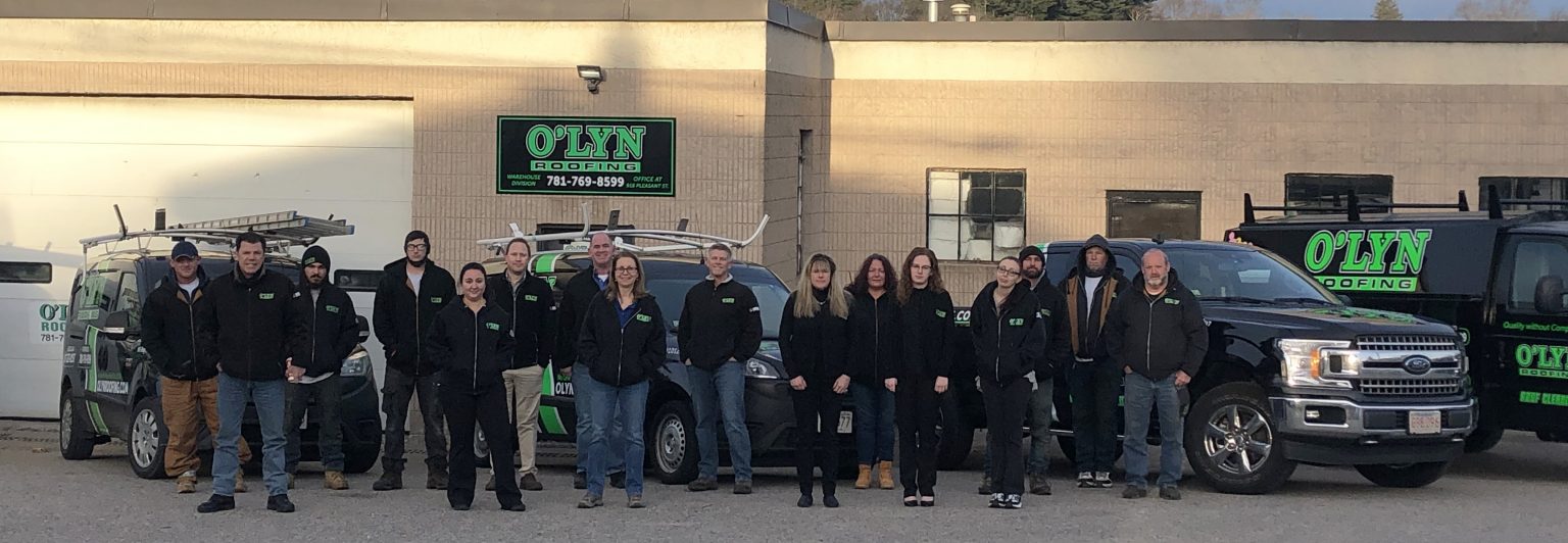 O'lyn Roofing's team standing outside in front of their office building.