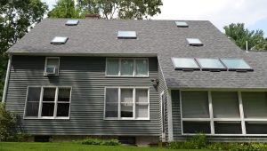 A two story gray home with a new roof and skylights installed by O'lyn Roofing.