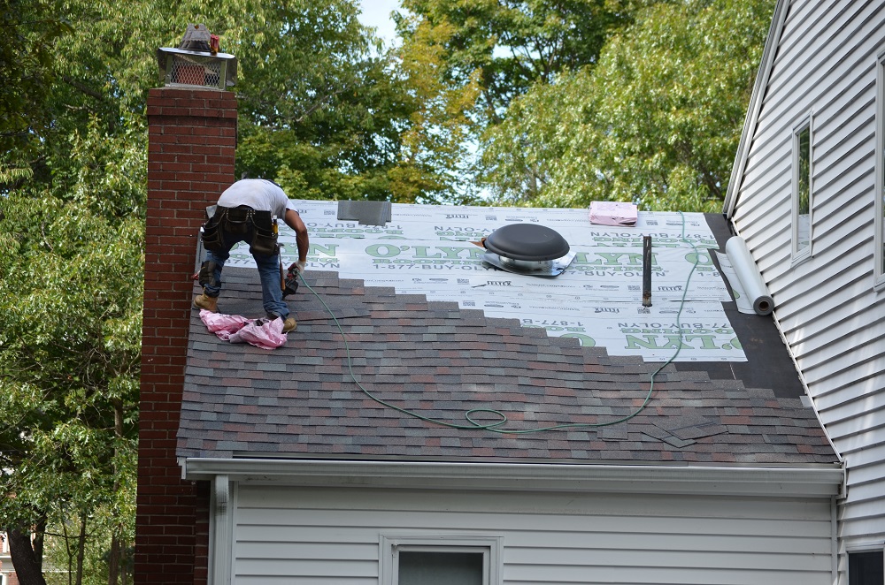 O'lyn contractor working on top of a residential home during a roof replacement job.