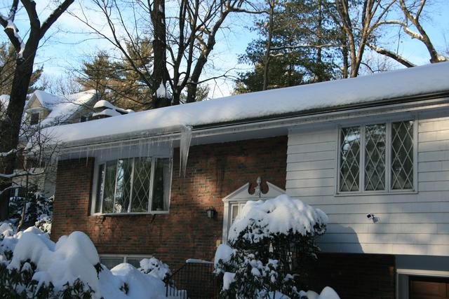 A home in winter covered in show with ice hanging from the roof.