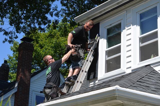 An O'lyn Roofing crew installing new gutters on a home in West Roxbury