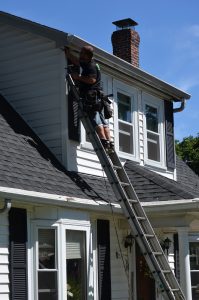 An O'lyn Roofing team member on a ladder working on a home.