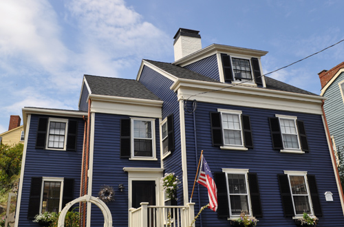 Two story home with blue siding near Boston with new gutters.
