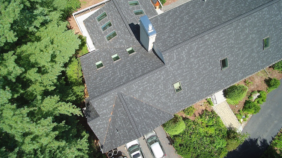 Arial view of a pitched roof on a home with new shingles and skylights.