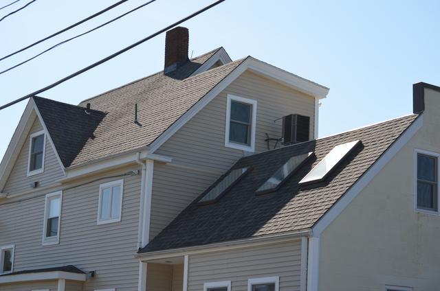 Before photo of a home in Needham of a roof and skylights in need of replacement.