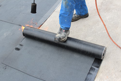 A man sealing new rubber roofing with a heat gun.