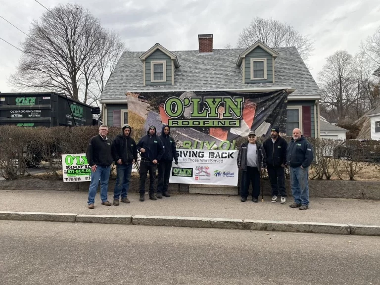 O'Lyn Roofing Crew gathered around a banner celebrating a new roof for a military veteran.