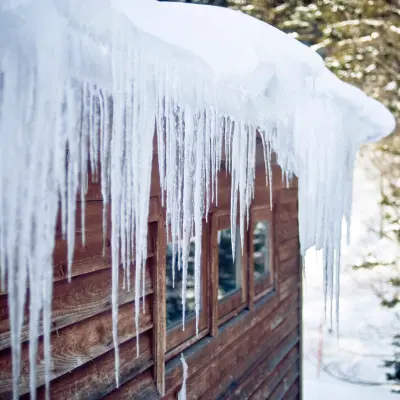 Icicles forming an ice dam on wood siding home 