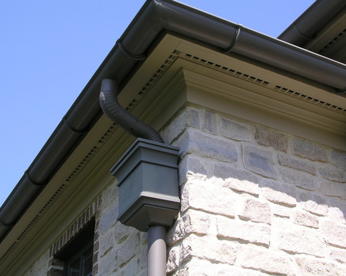  A brown gutter with an overflow box attached to a home. 