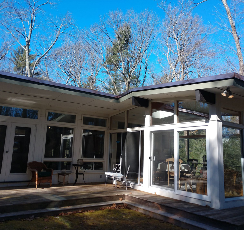 Modern home with large windows, sliding doors, and a stepped wooden deck.