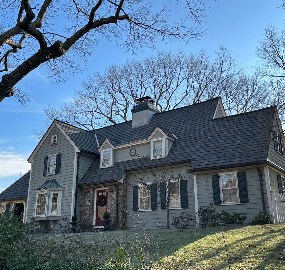Gray colonial style home with new dark asphalt shingle roof and dormers