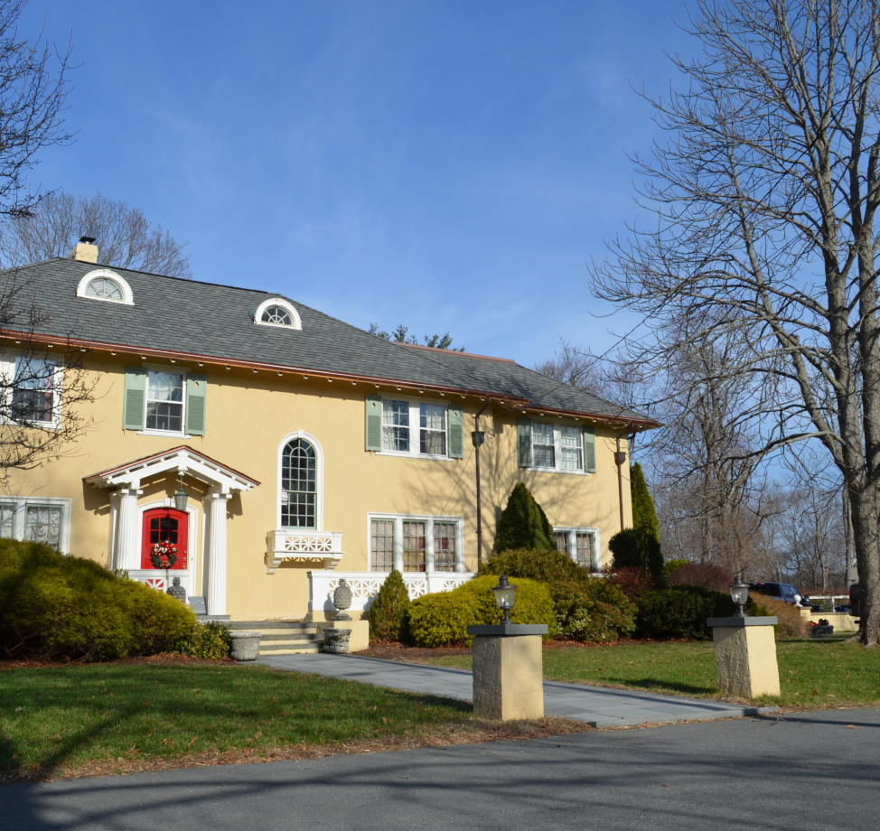 Two-story stucco home with red door and arched windows.