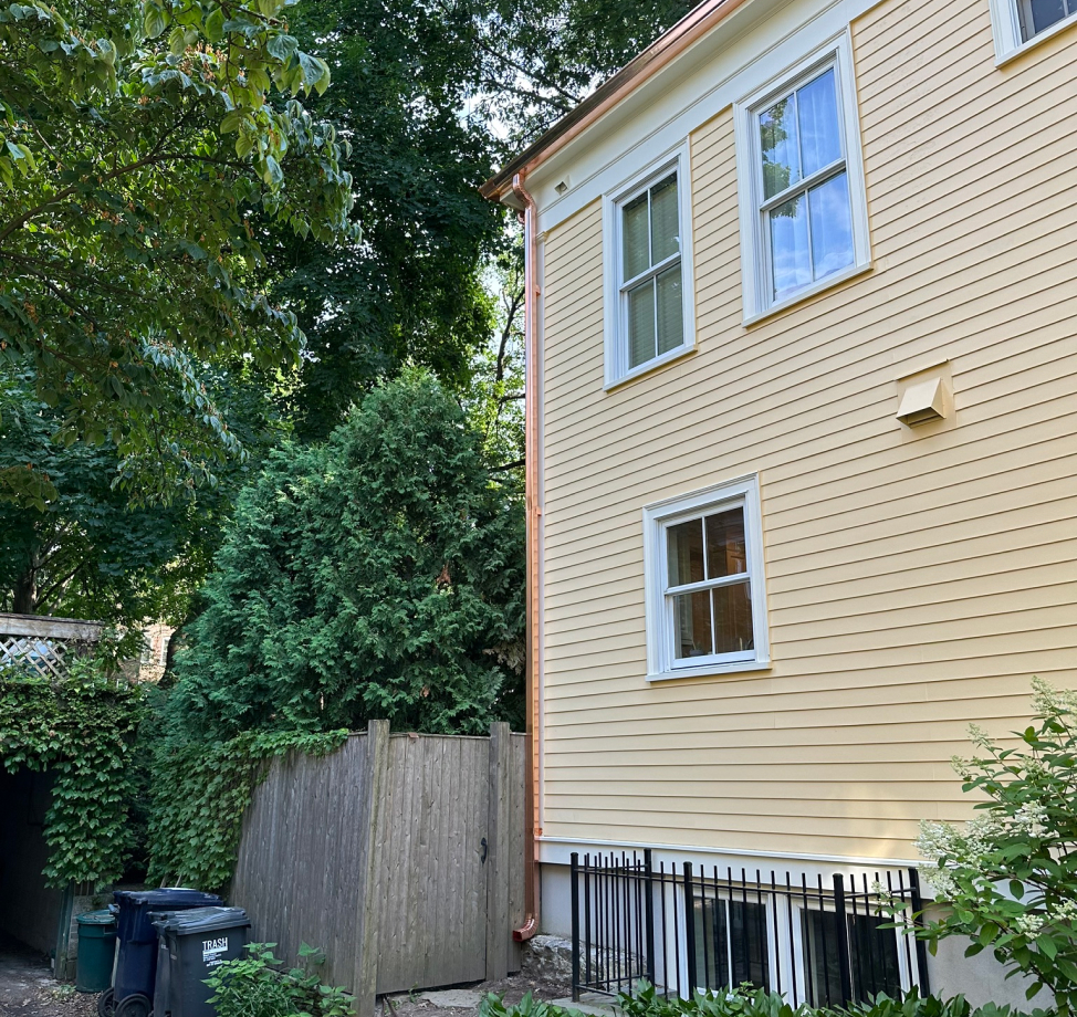 New copper downspouts installed on yellow siding home