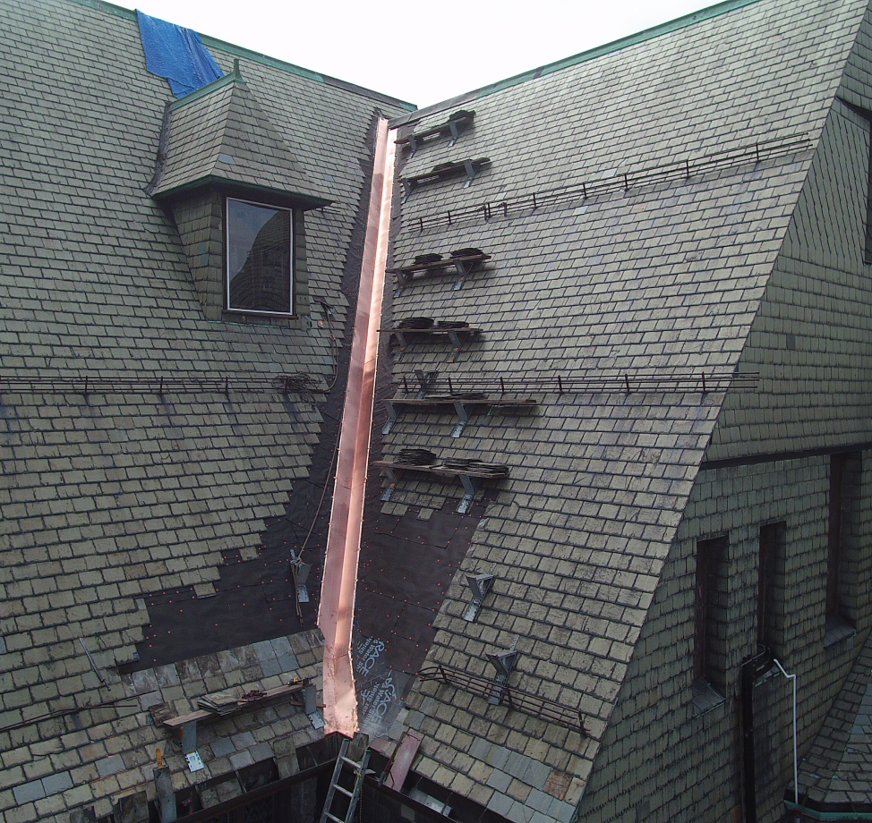 Slate roof repair with new copper valley flashing on historic building