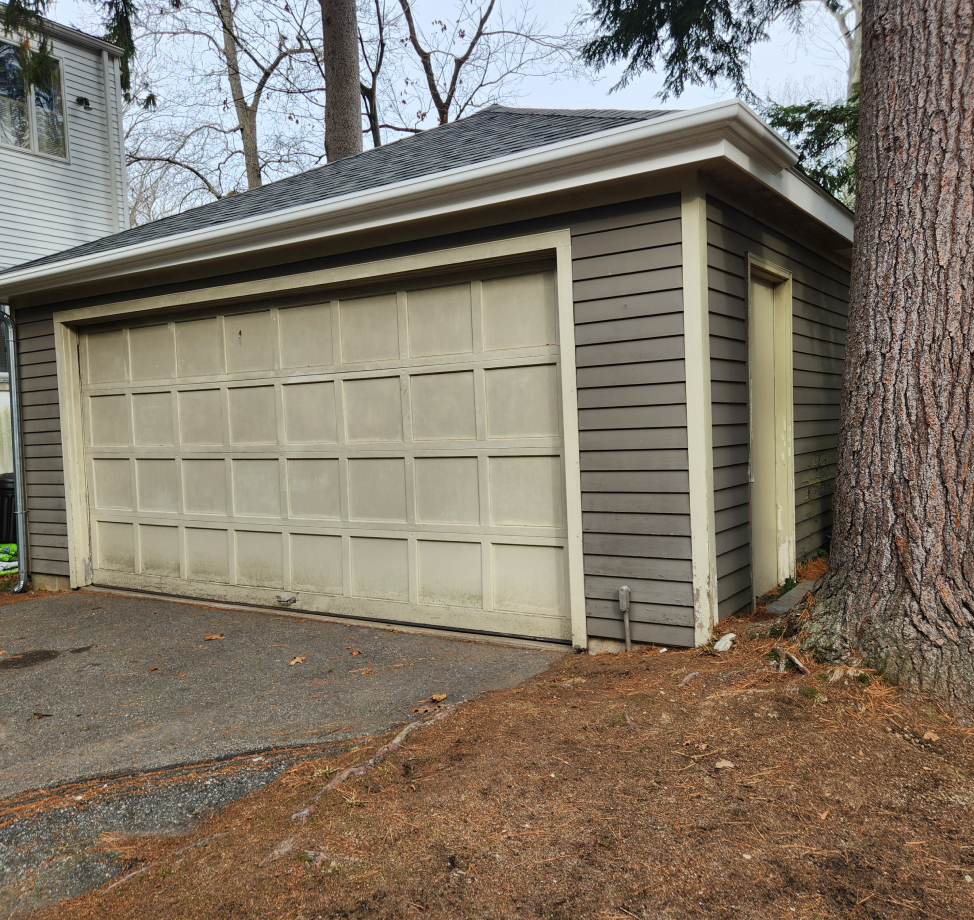 Detached garage with new dark asphalt shingle roof and gray siding