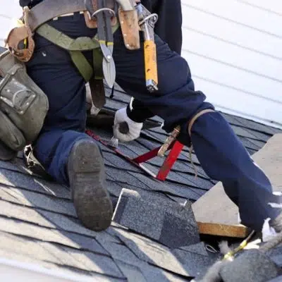 Roofer on a shingle roof removing shingles 