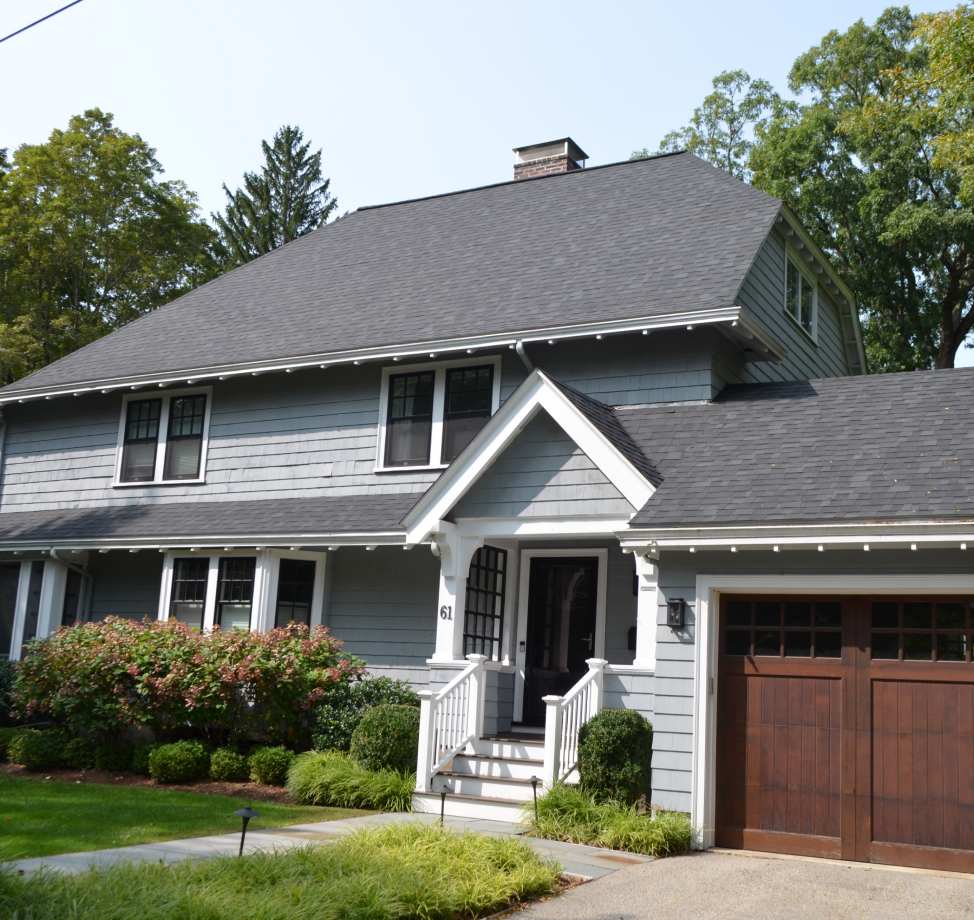 Gray shingle roof and wood-accented garage on a two-story home with white trim and blue siding.