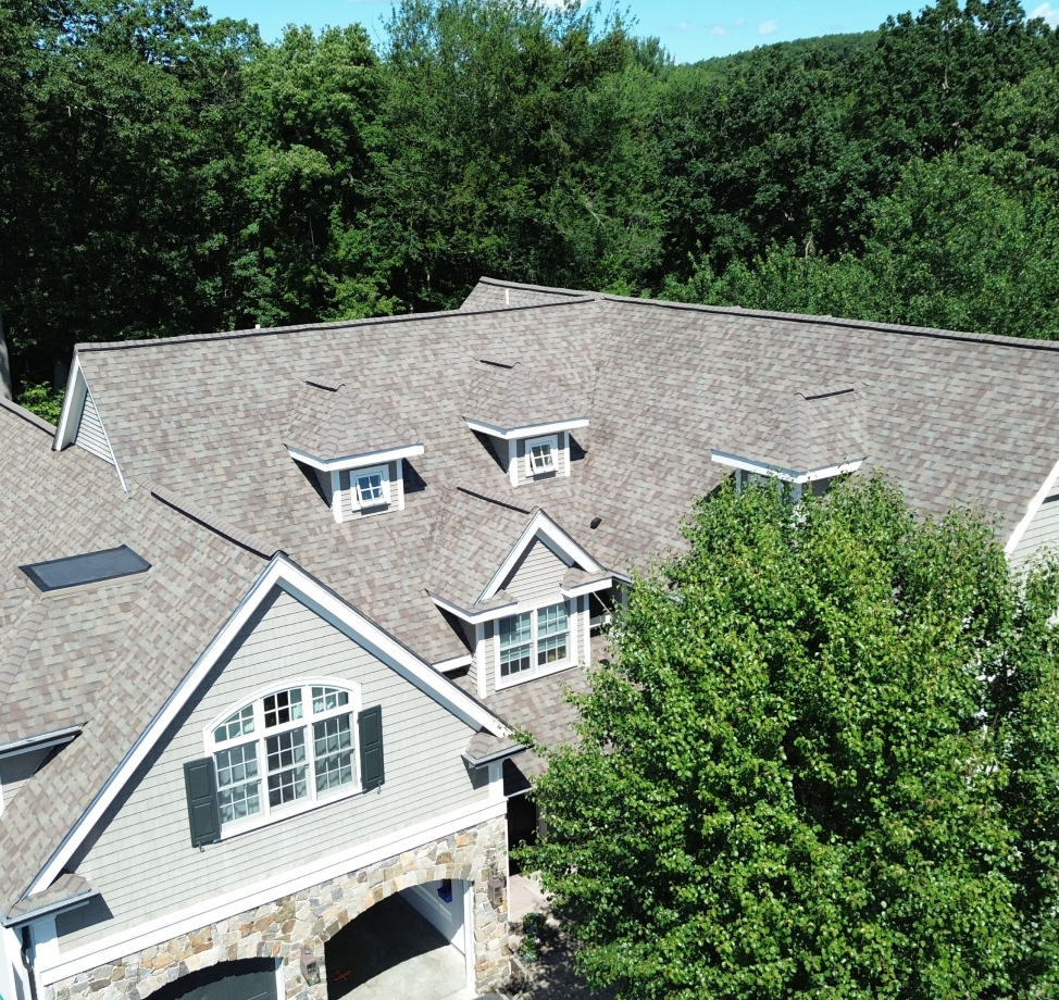 Large residential home with new brown asphalt shingle roof and dormers