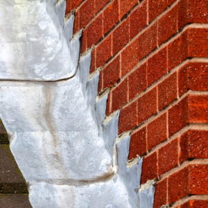 Close-up view of roof flashing installed along a brick wall for waterproofing.
