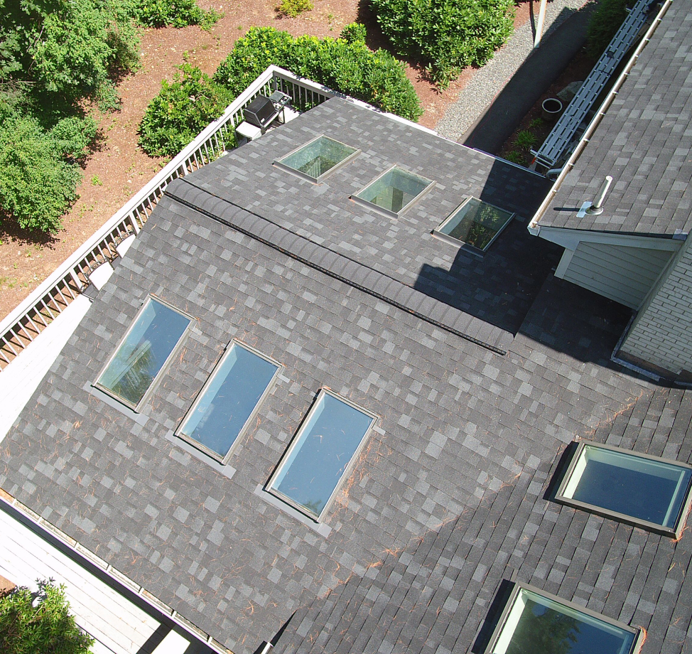 Dark asphalt shingle roof with multiple skylights and ridge vent