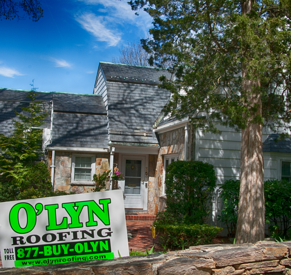 House with new roof and O'LYN Roofing yard sign in front.