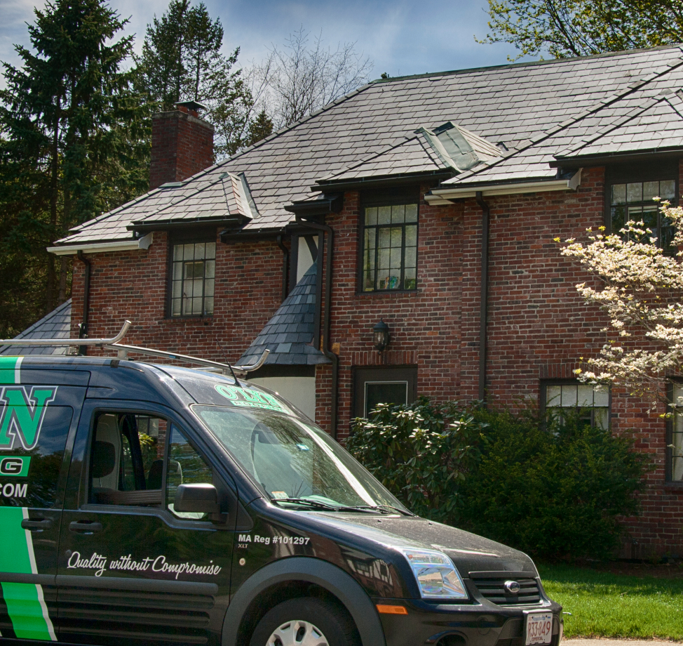 New slate roof on brick home with O'LYN Roofing service van in driveway