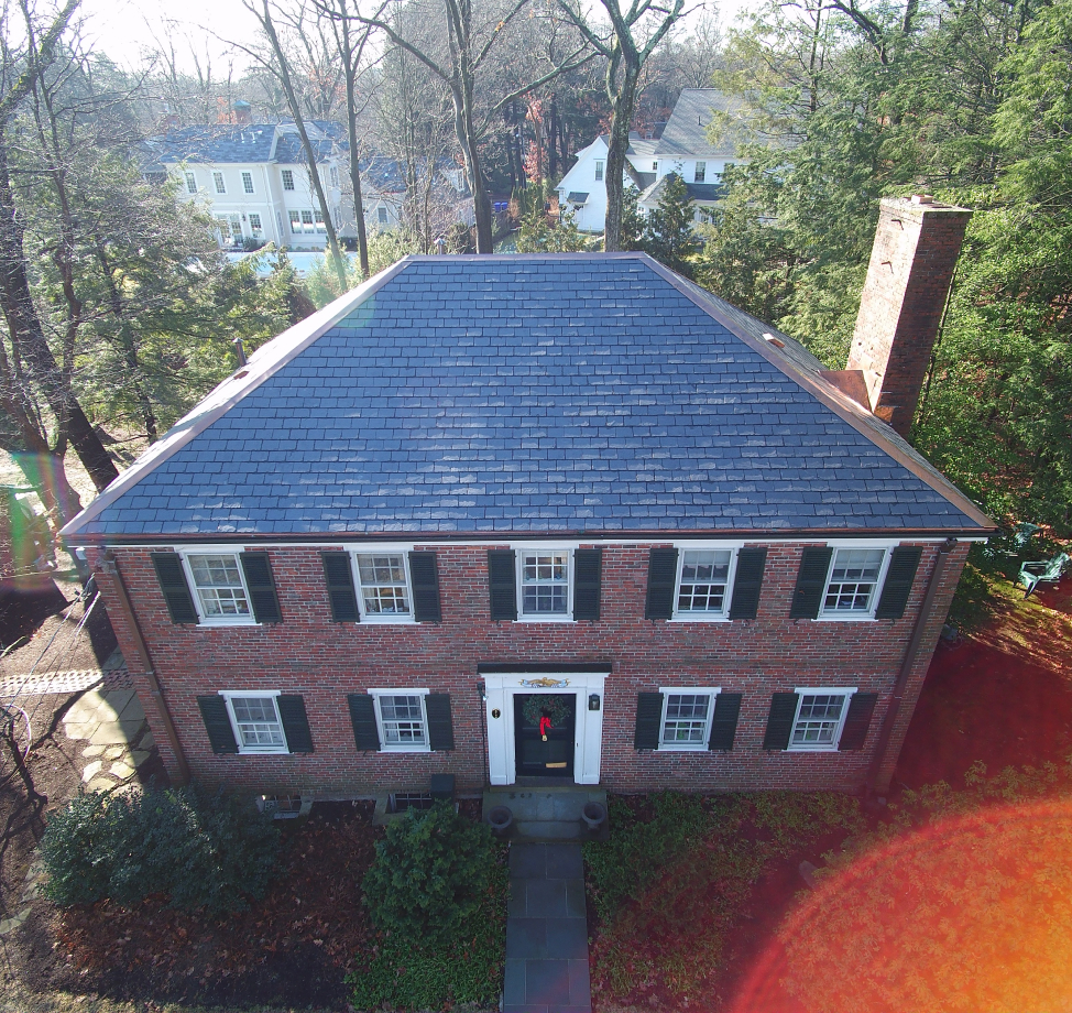 Aerial view of brick colonial home with new dark gray asphalt shingle roof